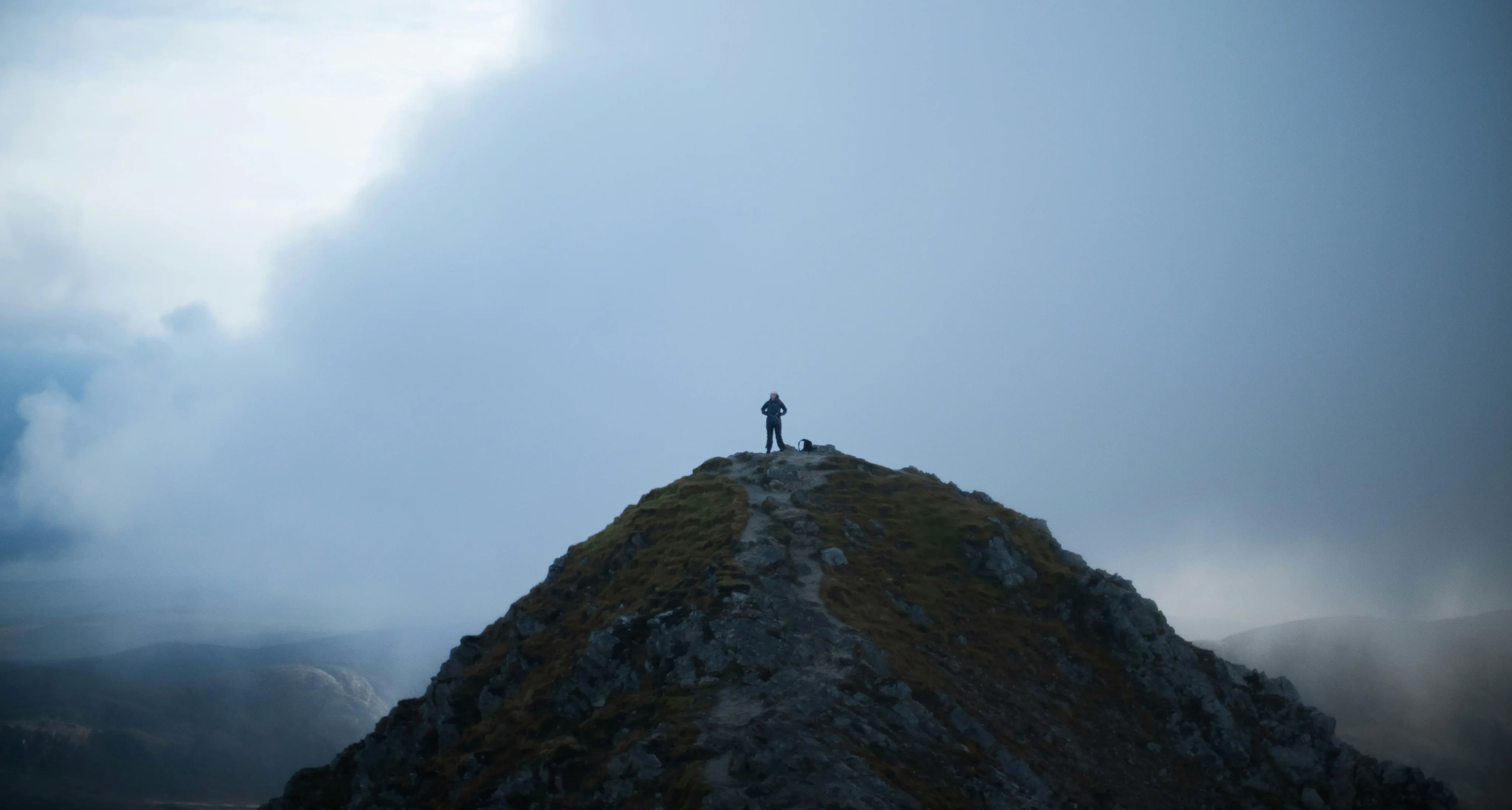 A figure standing on a mountain summit